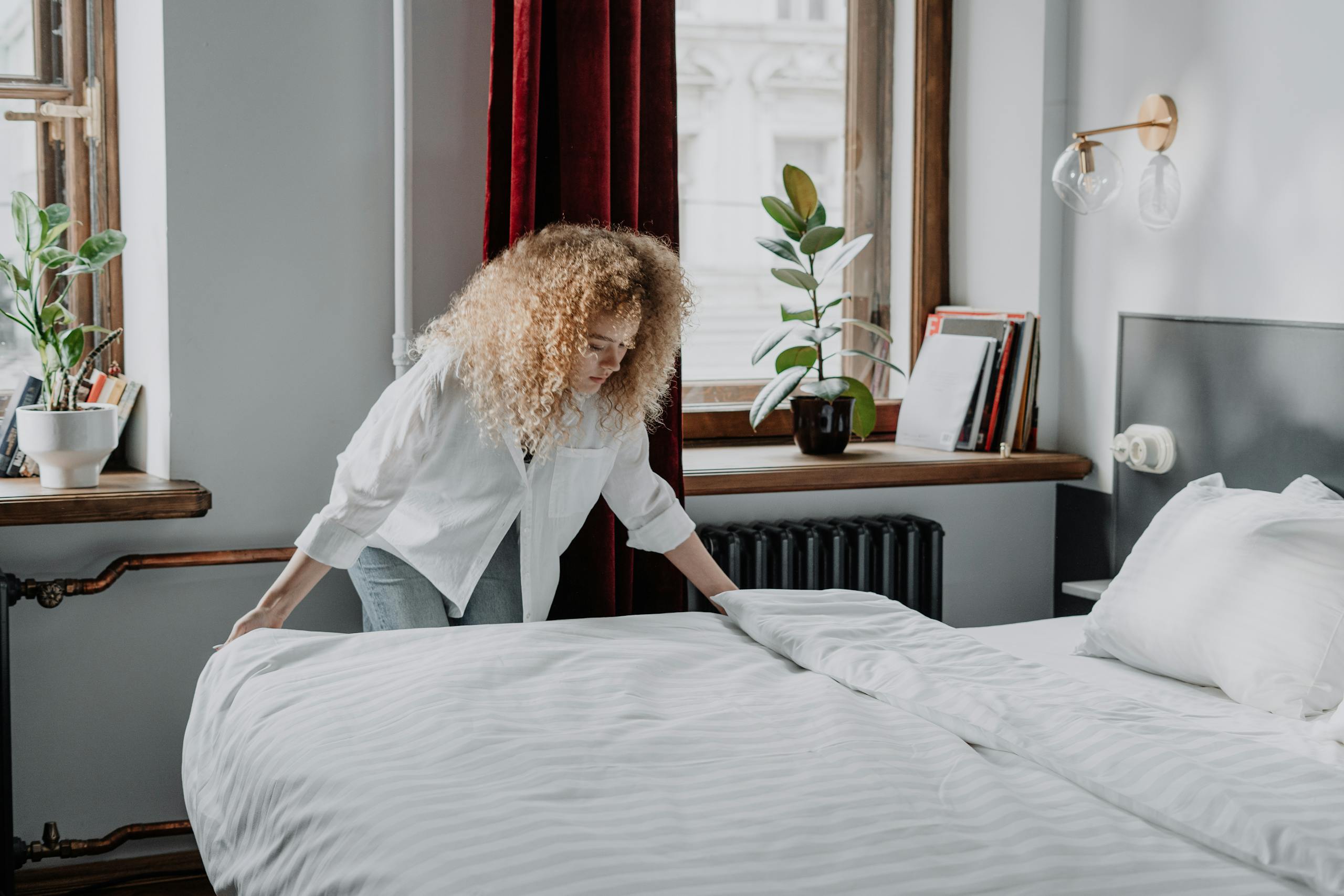 Woman in White Long Sleeve Shirt Sitting on Bed